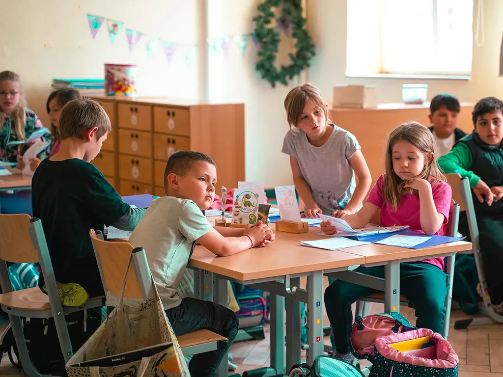 zeigt vier Kinder an einem Tisch in den Klassenräumen der Lukas-Backmeister-Schule bei einer Projektarbeit.