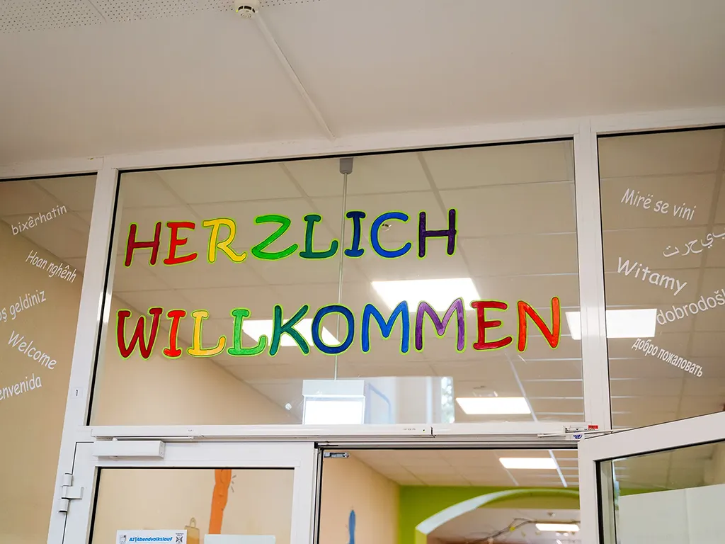 Hier ist eine Glastür der Luba Uelzen mit bunten Buchstaben. Dort steht, herzlich willkommen.