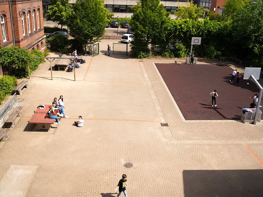 Schulhof der Luba Uelzen aus der Vogelperspektive mit Basketballplatz und Kindern auf einer Tischtennisplatte