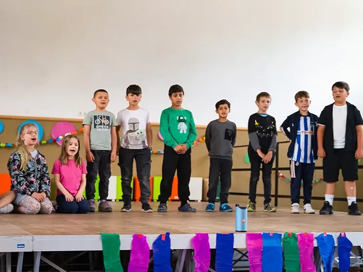 Zeigt Kinder auf einer Bühne der Lukas-Backmeister-Schule bei einer Veranstaltung.