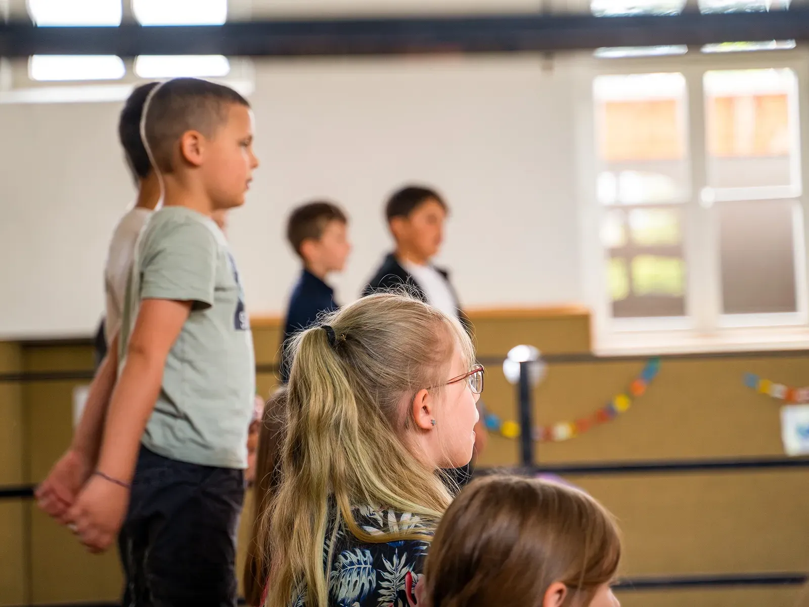 Zeigt Kinder auf einer Bühne, von der Seite fotografiert bei einer Veranstaltung der Lukas-Backmeister-Schule.