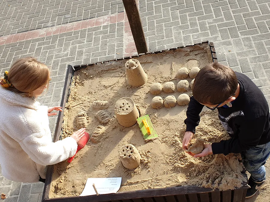 Zeigt Kinder der Lukas-Backmeister-Schule auf dem Schulhof, die in einer Sandkiste spielen.