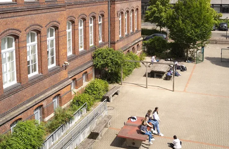 Den Schulhof aus der Vogelperspektive, an der linken Bildseite erkennt man das Backsteinschulgebäude.