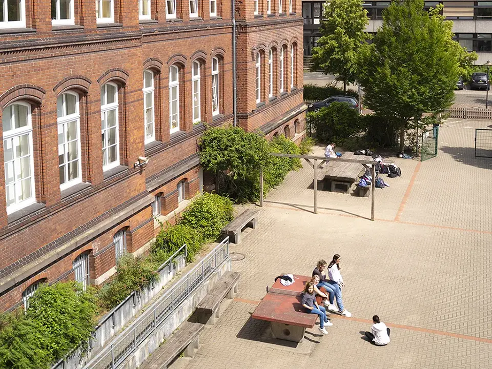 Den Schulhof aus der Vogelperspektive, an der linken Bildseite erkennt man das Backsteinschulgebäude.