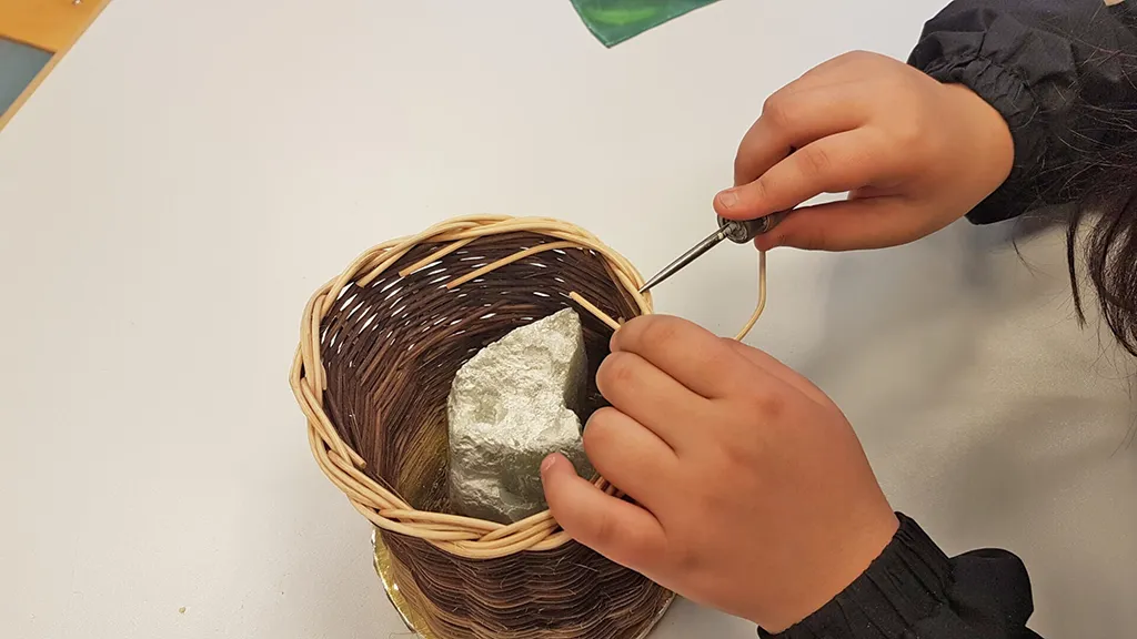 zeigt ein Kind in der Ergotherapie der Bearbeitung eines Korbes